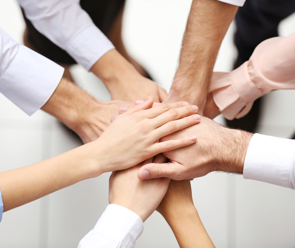Colleagues stacking their hands together in a symbol of teamwork